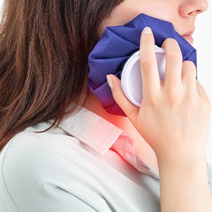 A woman holding an icepack to her face