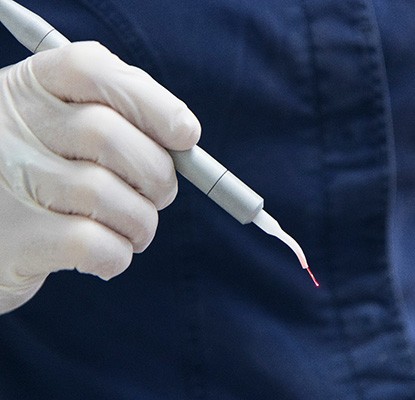 a dentist holding a soft tissue laser