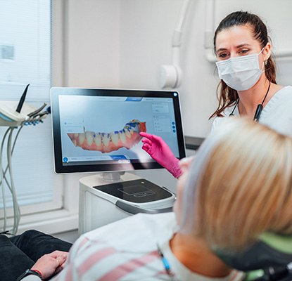 a dental assistant showing a patient a digital impression of her mouth on a computer screen