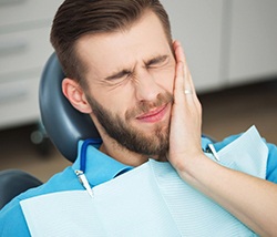 Man in dental chair holding jaw