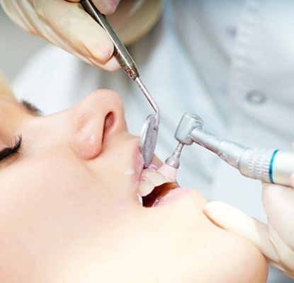 dentist cleaning patient’s teeth