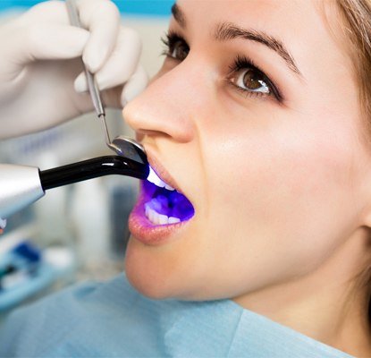 A curing light being used on a woman with a filling