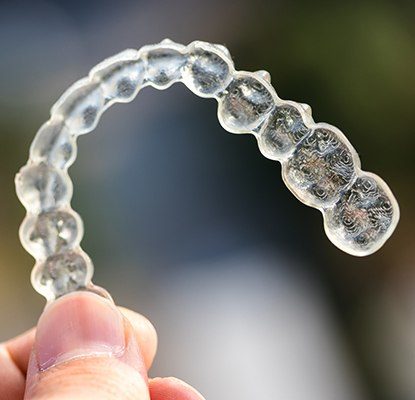 Hand holding a clear aligner