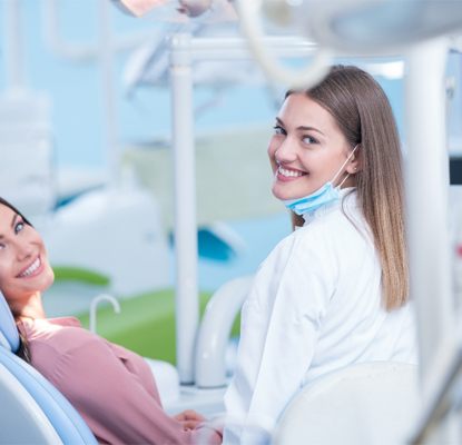 A young woman in the dentist chair with her dentist next to her