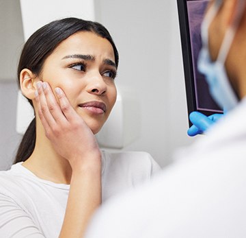a woman holding her mouth because she has a toothache