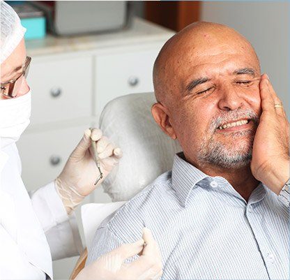 Man in dental chair holding jaw