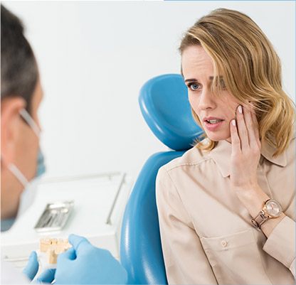 Woman in dental chair holding jaw