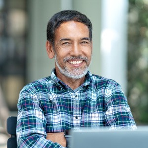 Man with dental implants smiling and crossing his arms