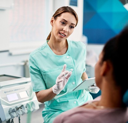 Dental assistant explaining cost of Invisalign to patient