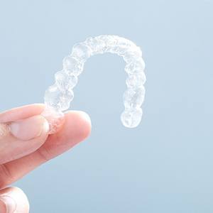 Patient holding up their Invisalign aligner