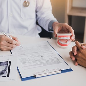 Dentist reviewing insurance paperwork on desk next to X-ray