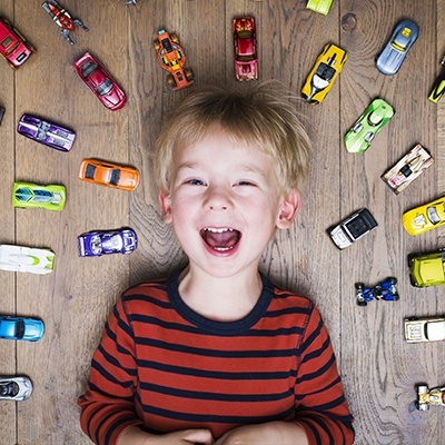 Laughing little boy surrounded by toy cars
