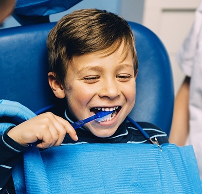 Little boy in dental chair practicing tooth brushing