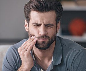 Man in pain holding jaw