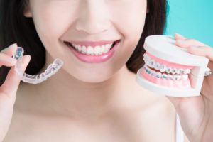 person holding braces and Invisalign aligners