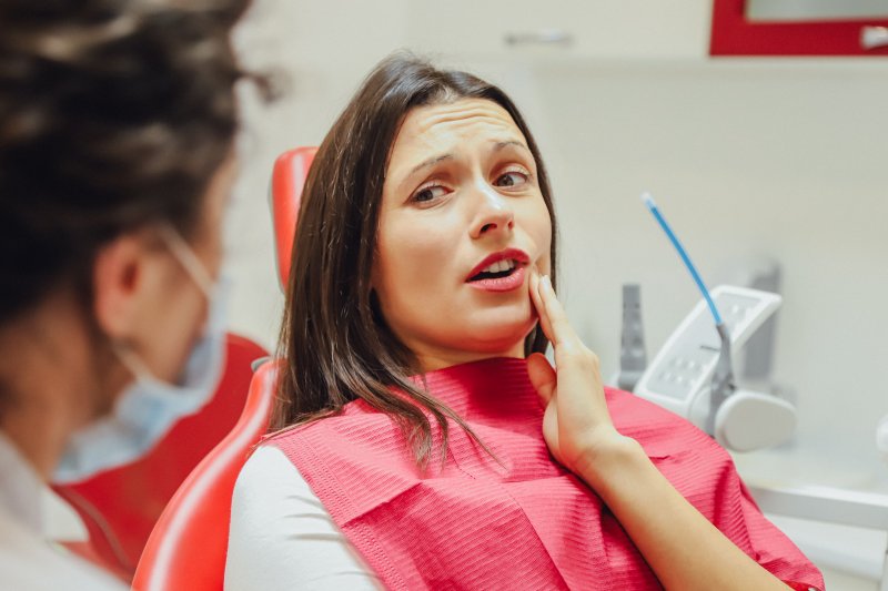 a young woman holding her mouth in pain in preparation for oral surgery