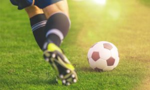 Closeup of soccer ball and player wearing cleats