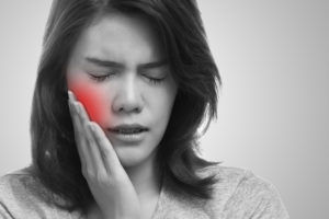 Woman with toothache pressing her cheek with painful expression 