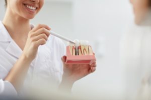 dentist showing a patient a model of dental implants 